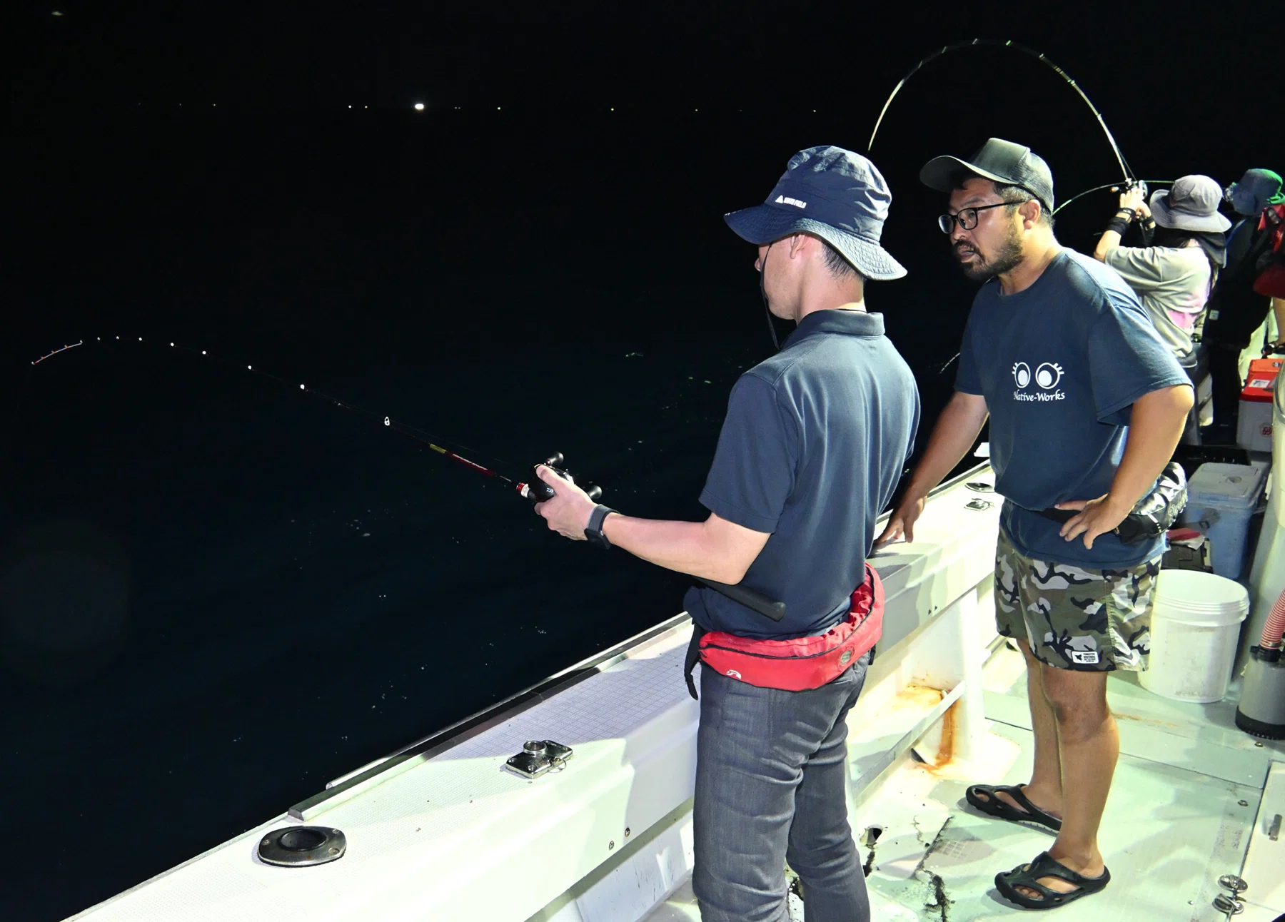 金沢・金石港から出航するイカ釣り漁船で客にイカ釣りを教える高根さん(撮影:2025年7月 加藤直人)